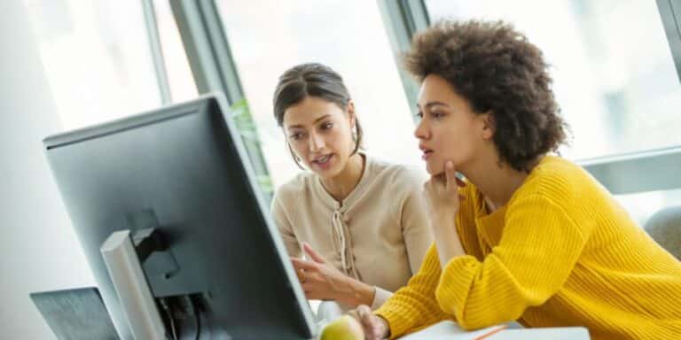 Two female market researchers discuss market research questionnaire