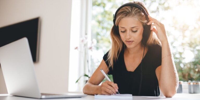 Young woman listening to a market research recording on headphones to transcribe it