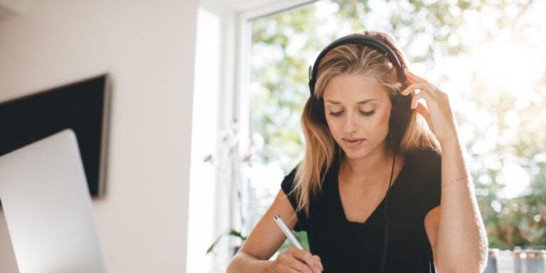 Young woman listening to a market research recording on headphones to transcribe it