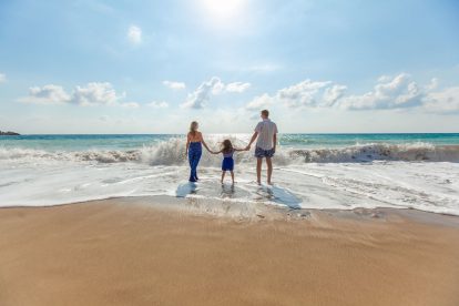 Man, woman and daughter on a sunny beach while on holiday