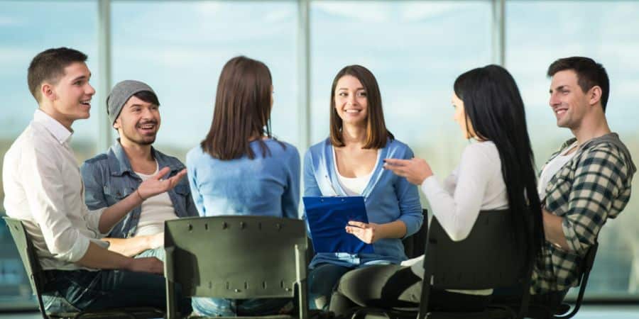 A focus group group of young adults with a female moderator