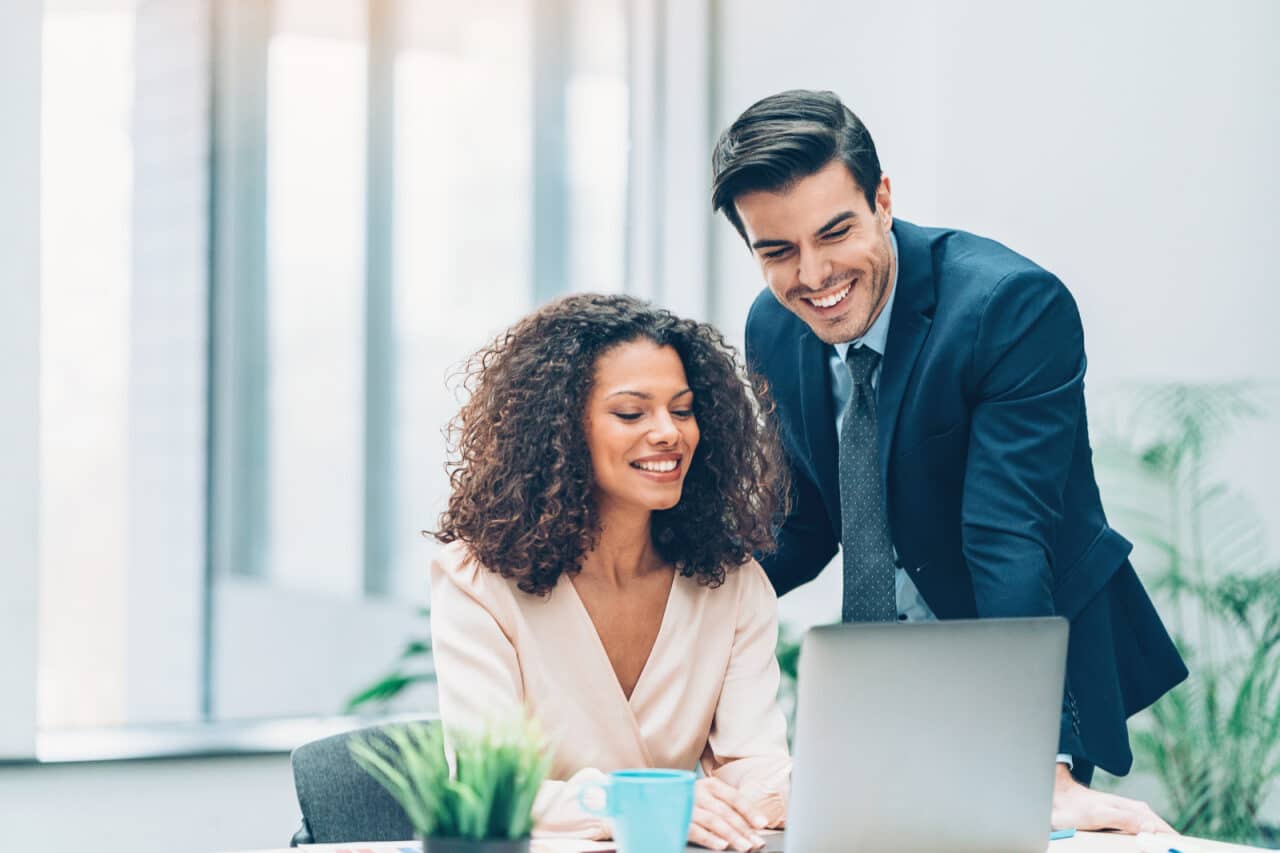 A women showing a man a screener on her laptop