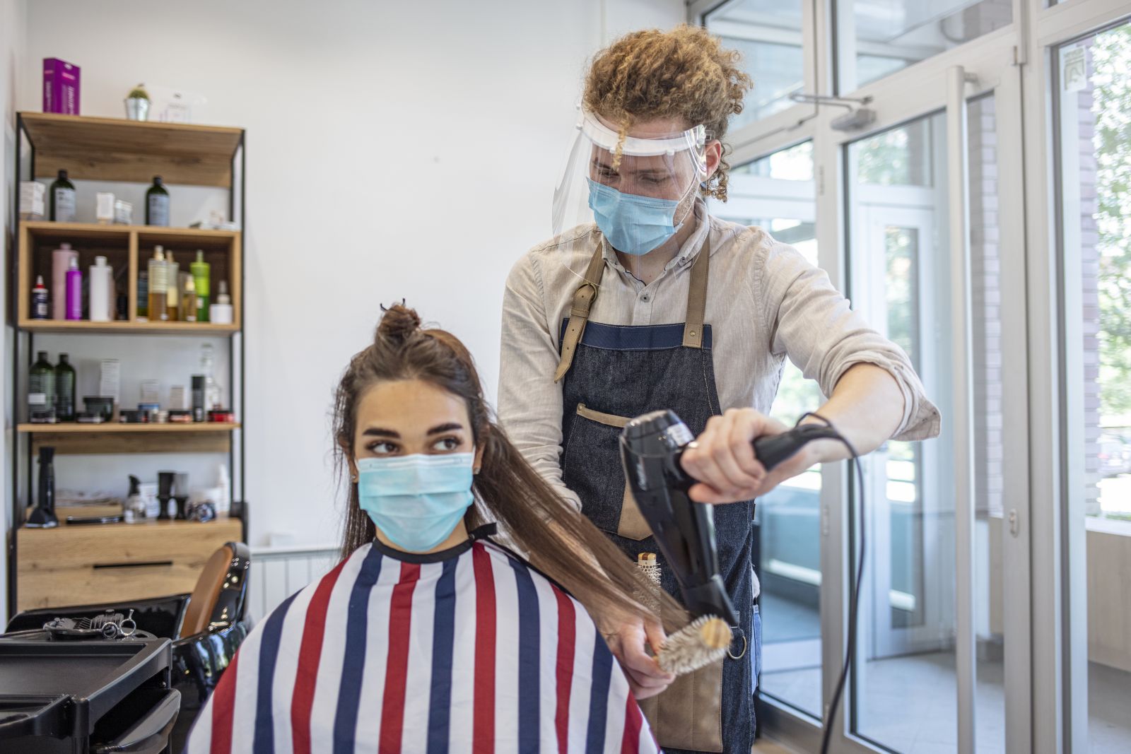Hairdresser blow-drying customer's long hair during COVID