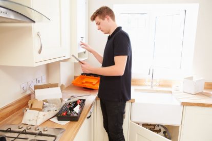 Young male engineer completing tests after installing a new central heating boiler in a kitchen