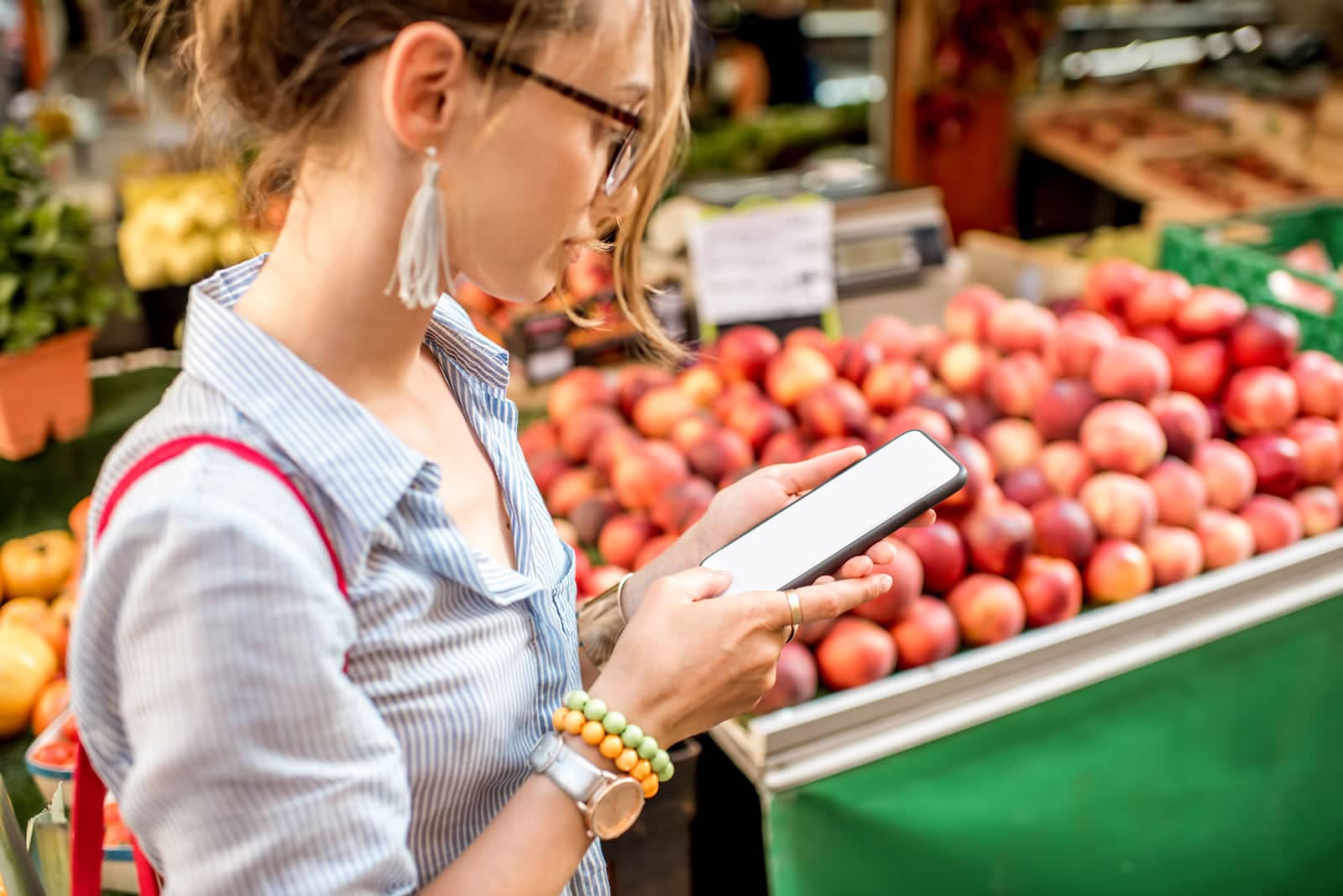 Young woman using smartphone standing in front of the food market in France