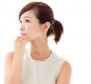 Head and shoulders image of pensive young East Asian woman