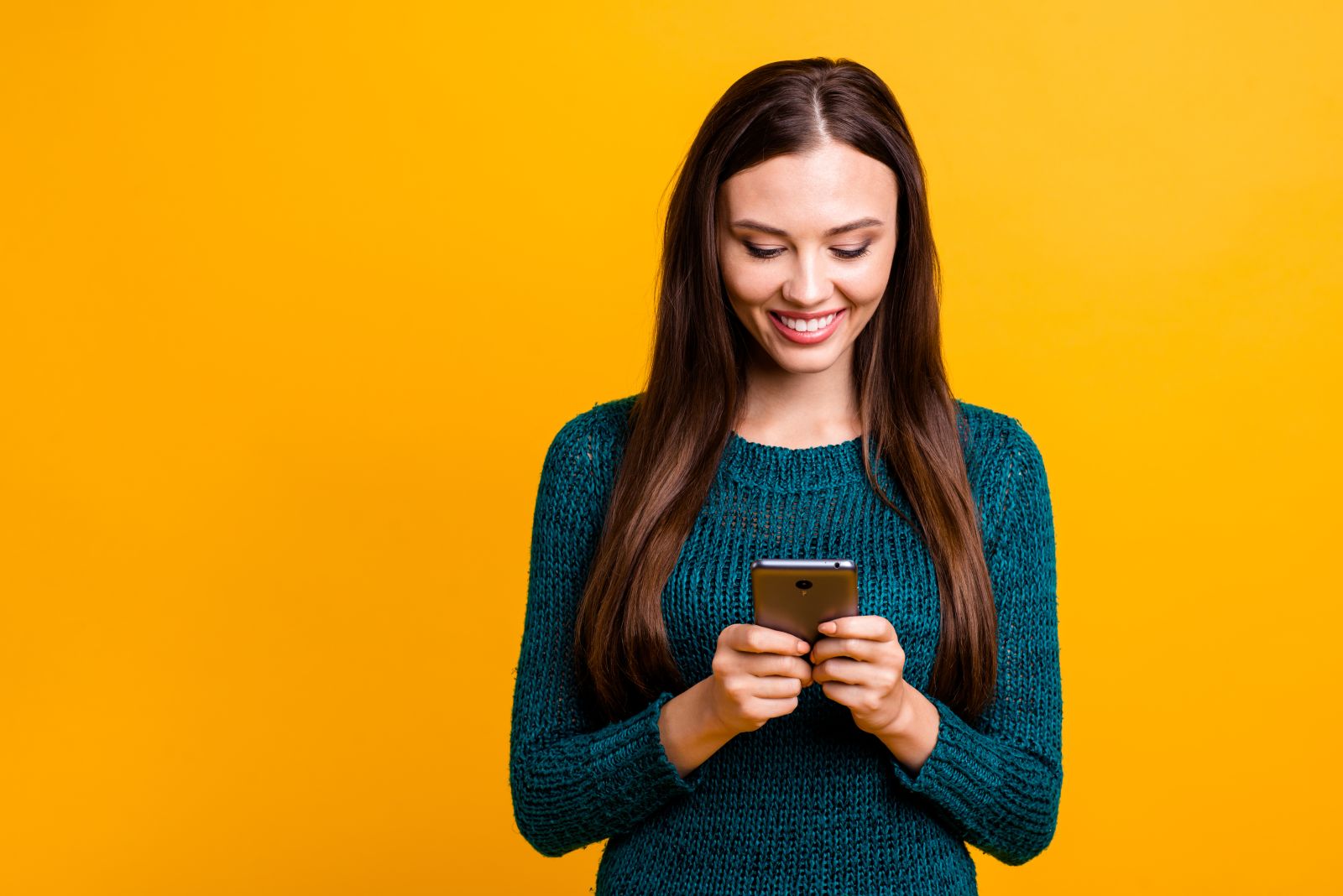 Young female respondent testing an app (standing against a bright yellow background)