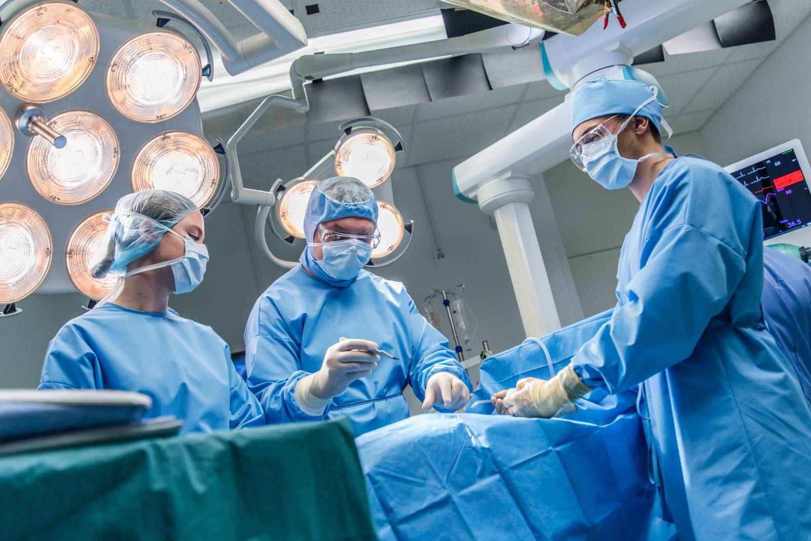 Surgeon and two assistants in operating theatre