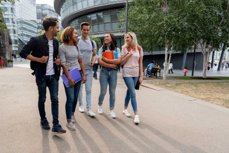 Diverse group of students walking on the street talking and holding notebooks - lifestyle concepts
