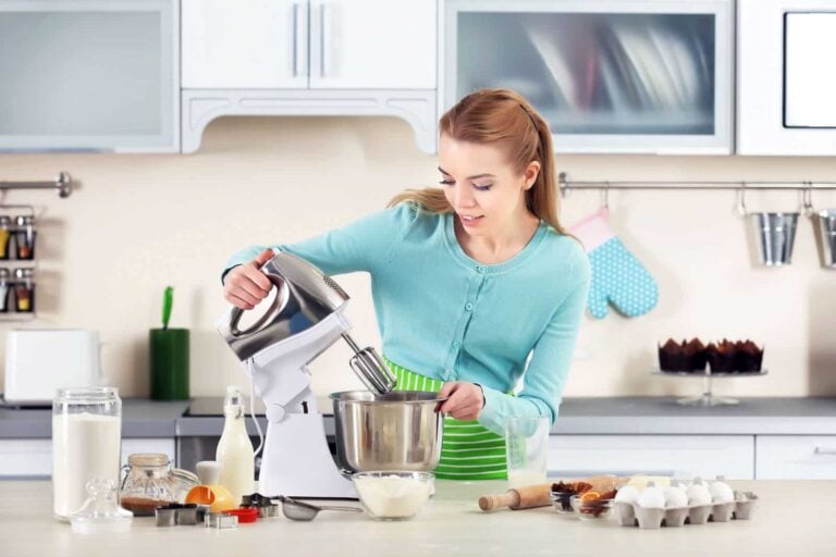 german woman using food mixer to make a cake in her kitchen full of appliances