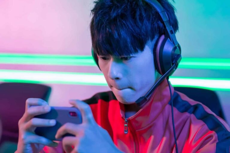 japanese teenager with headpgones playing mobile game on phone