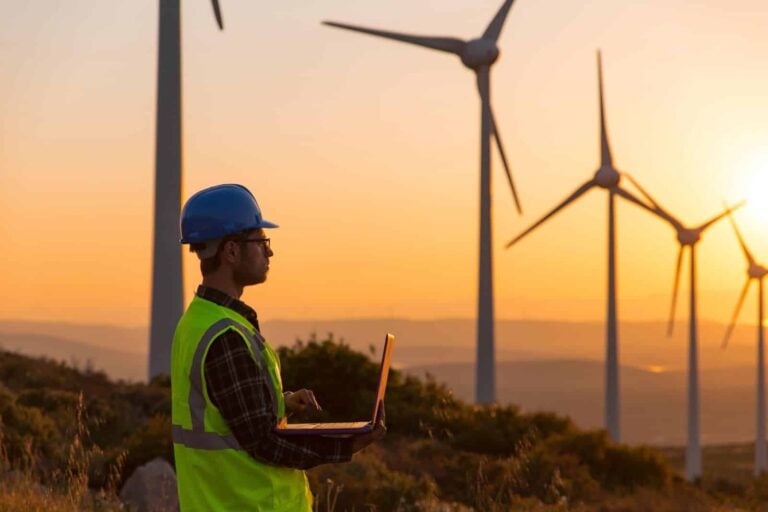 Maintenance engineer in wind turbine farm at sunset