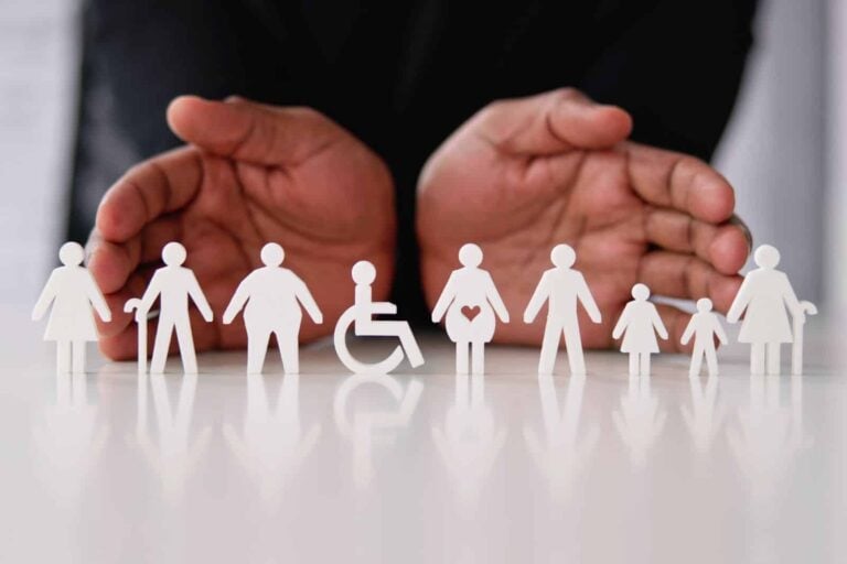 Male hands showing cut-out paper figures representing diversity