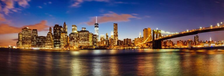 New York City, USA - view of Manhattan from Brooklyn at dusk with One World Trade Center visible in the centre and Brooklyn Bridge illuminated on the right