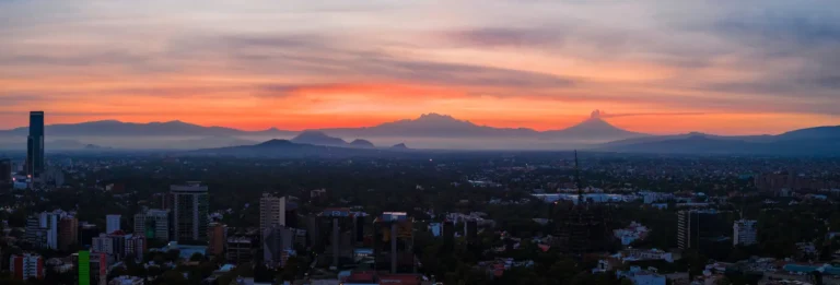 Mexico City, Mexico - panoroma at dawn with volcanoes and ash cloud in the distance