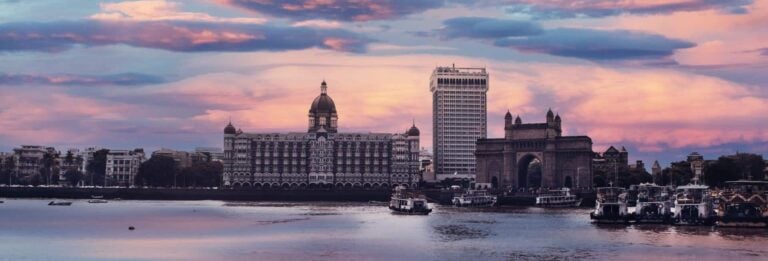 Mumbai, India - cityscape at dusk against colourful sky with ferries in the foreground