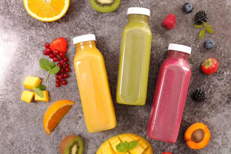 selection of fresh bottled juices and pieces of fruit on gray background