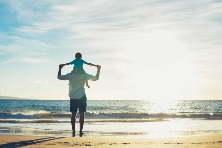 Father and son playing on the beach at sunset