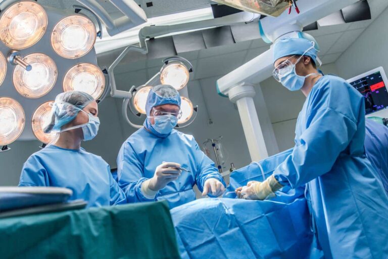 electrophysiologist surgeon and two assistants wearing ppe in hospital operating theatre