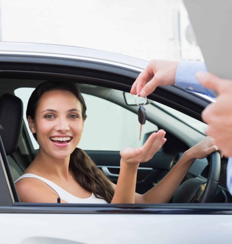 Smiling young woman receiving the keys to a car she has just bought