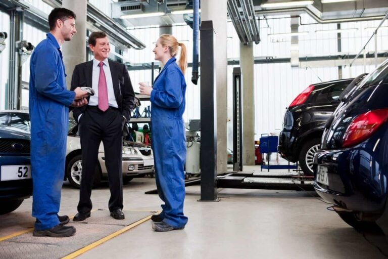 garage owner talking to two mechanics in a repair garage