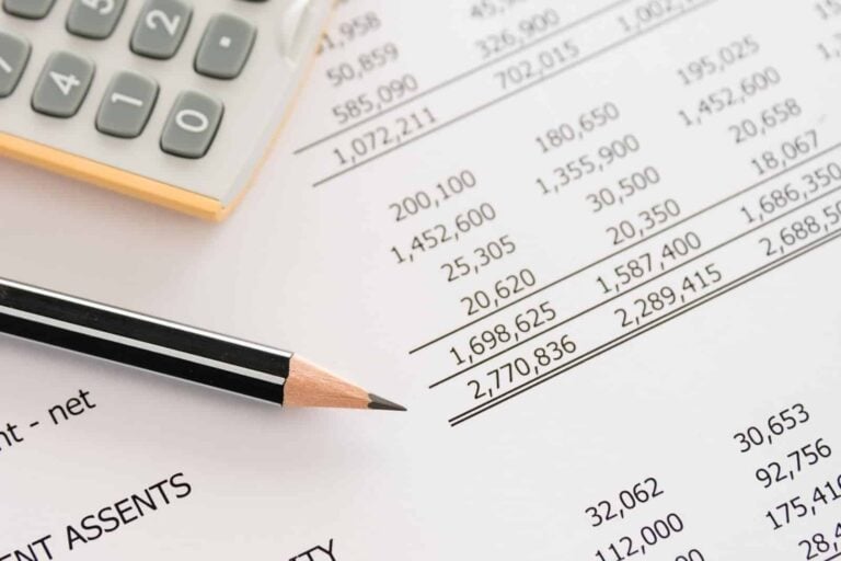 Close-up shot of a printout of a balance sheet with pencil and calculator visible