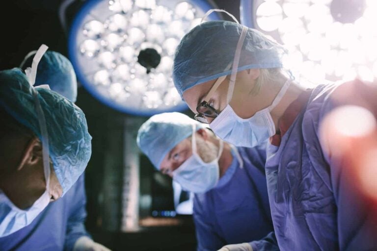 Concentrated female surgeon performing surgery with her team in hospital operating room. Medics during surgery in operation theater.