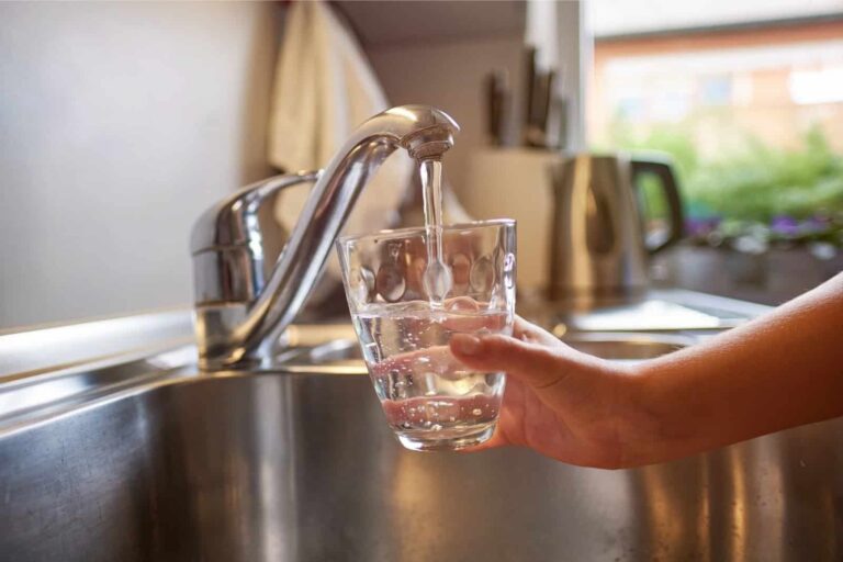 Consumer filling glass tumbler from kitchen tap