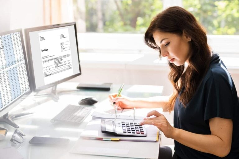 female accountant using calculator and virtual accounting software on company pc