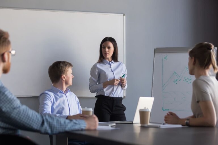 Female moderator writing on a flipchart during focus group. Two male and one female respondent are also visible