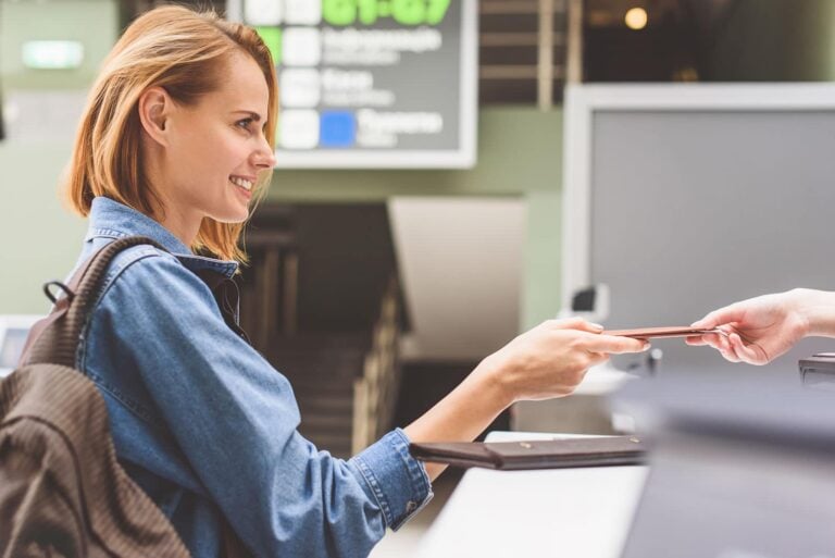 female tourist showing her passport at airport check-in desk in terminal