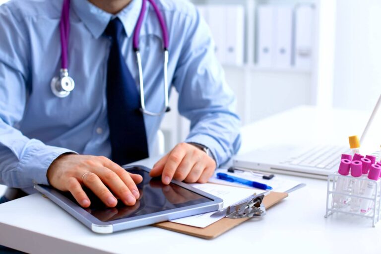 healthcare professional seated at desk using tablet to go through patient medical records