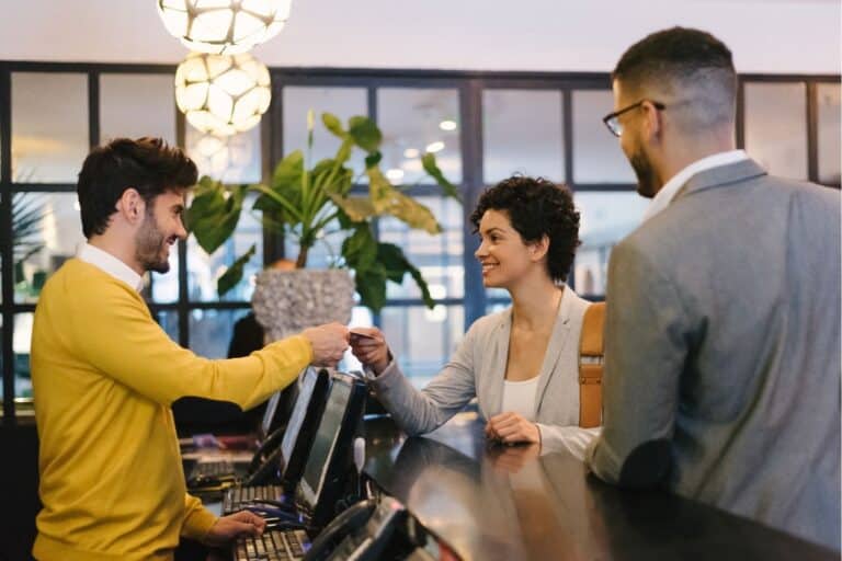 hotel receptionist hands over room key card to guests