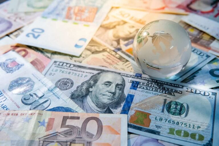International money transfers - glass globe standing on banknotes from different countries