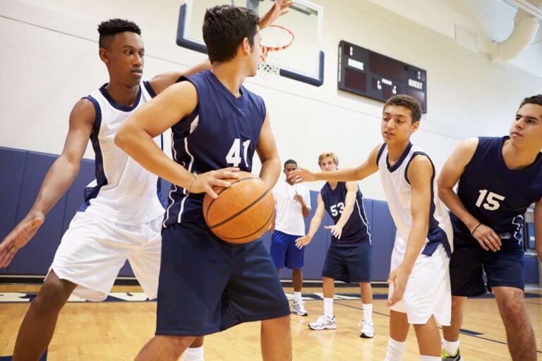 Male school teams playing basketball in gym