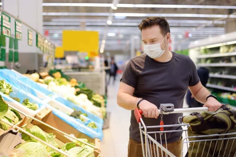 man wearing covid mask while shopping in supermarket looking for cruelty free vegan products