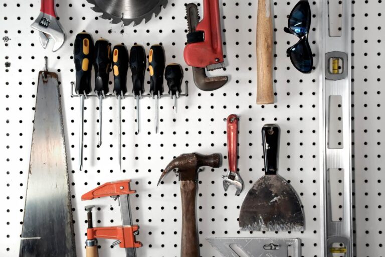 various carpentry tools hammer screwdrivers saw measurer stored in a garage on a pegboard