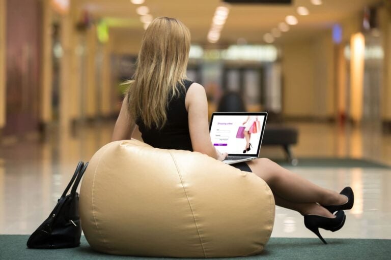 smartly dressed woman shopping for fashion items online while seated in an indoor mall