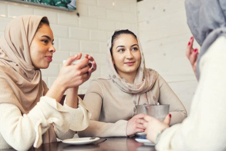 young moroccan women holding teacups and talking in a cafe