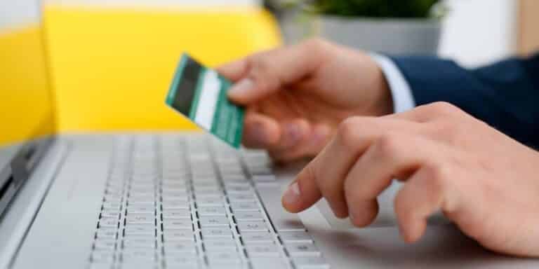 Businessman entering bank card details for a financial transaction on a laptop computer