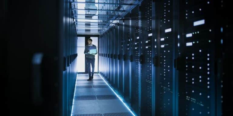IT professional using a laptop to check the status of servers in a data centre