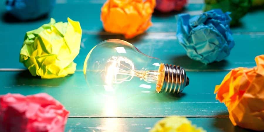 Incandescent bulb and colorful notes on turquoise wooden table