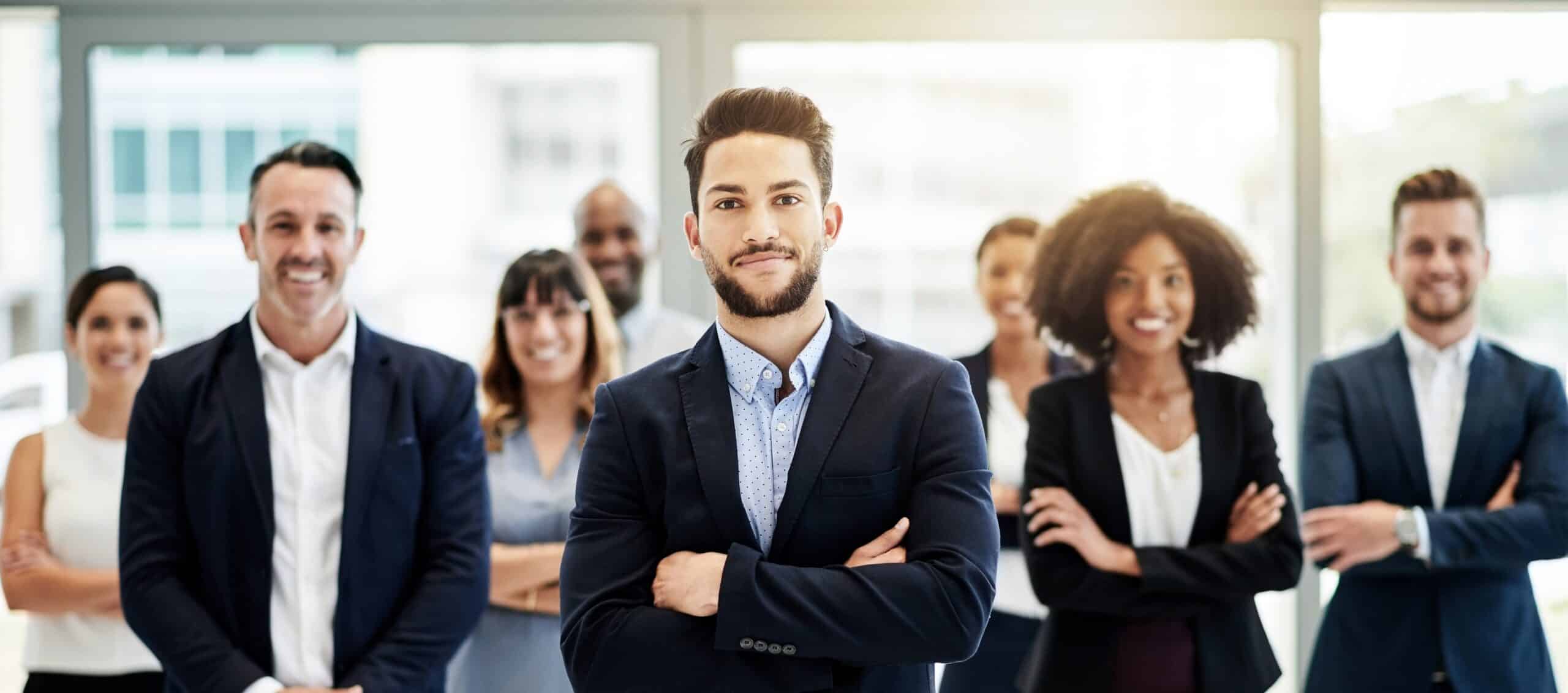 Ready to help - a group of business people standing and smiling with their arms folded