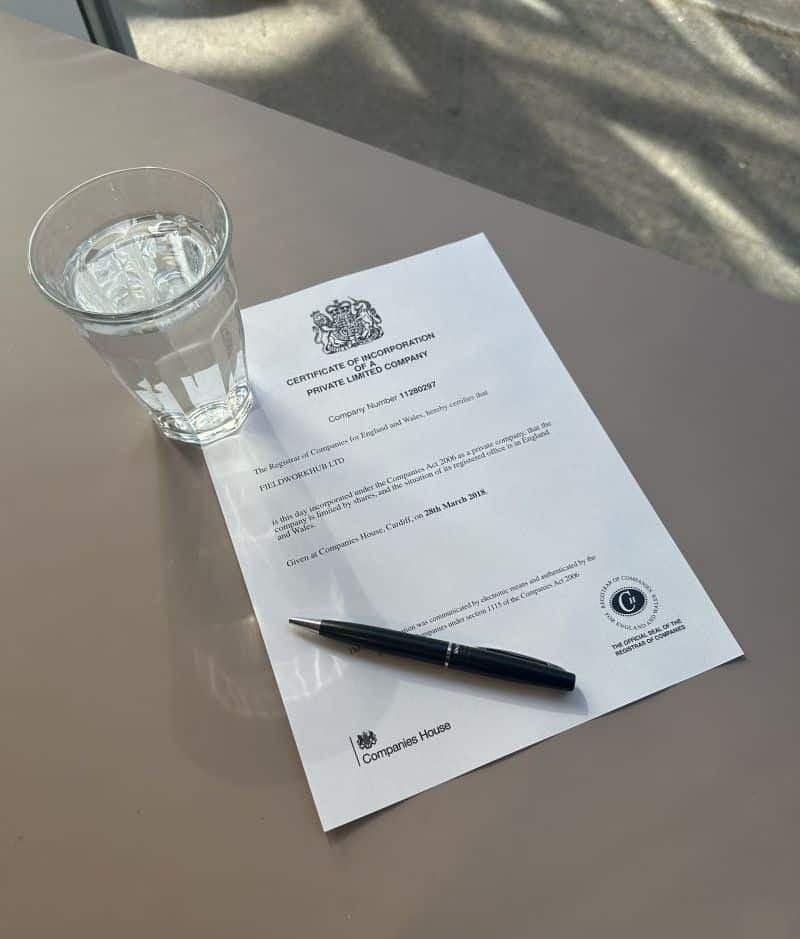 FieldworkHub Certificate of Incorporation laid out on a desk with a pen and a glass of water