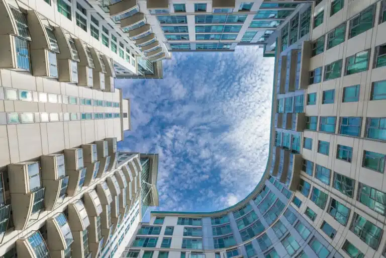 Modern new build apartment buildings in London borough - view upwards from the courtyard to the blue sky above